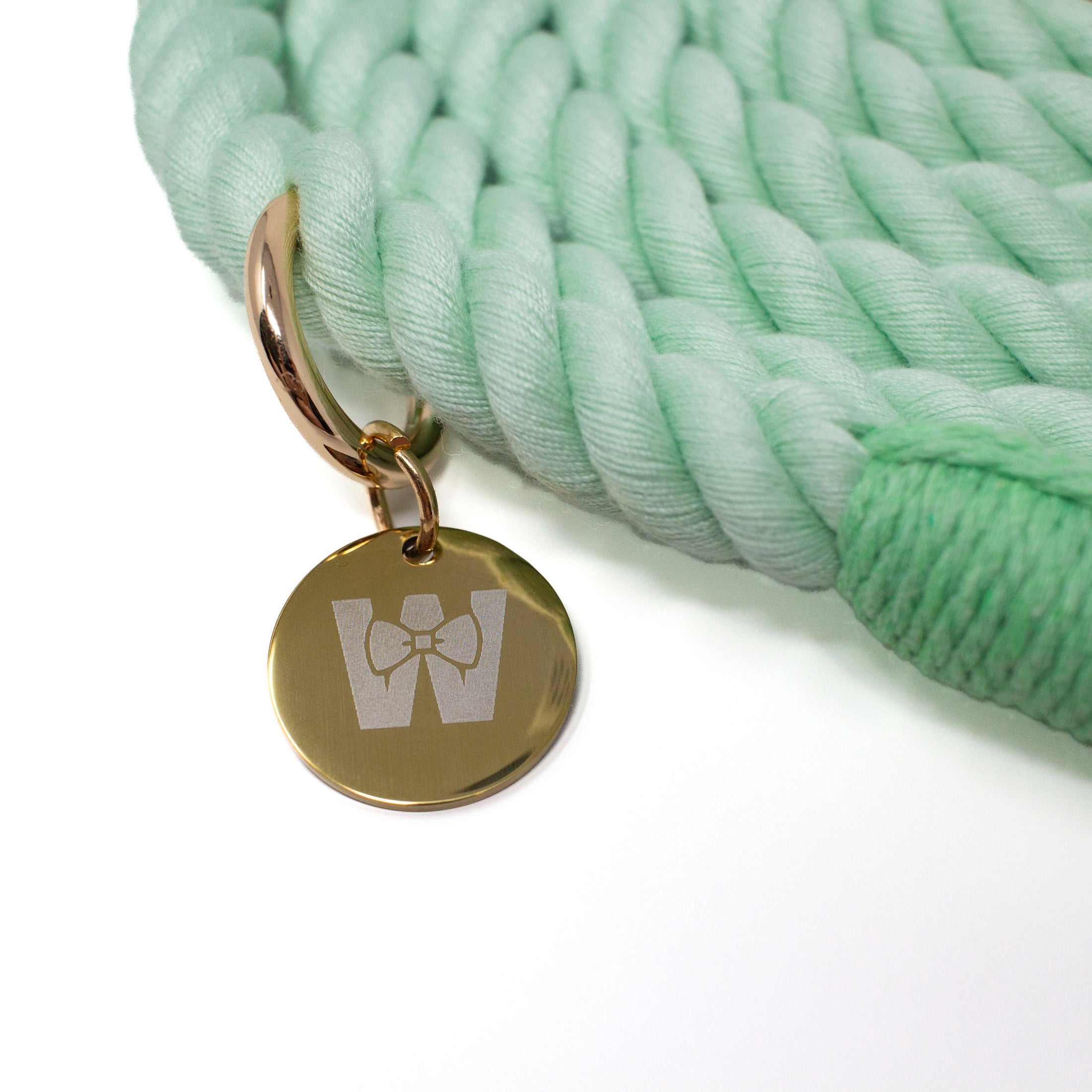 Light green braided rope leash with a gold tag featuring The Woofdrobe logo on a white background
