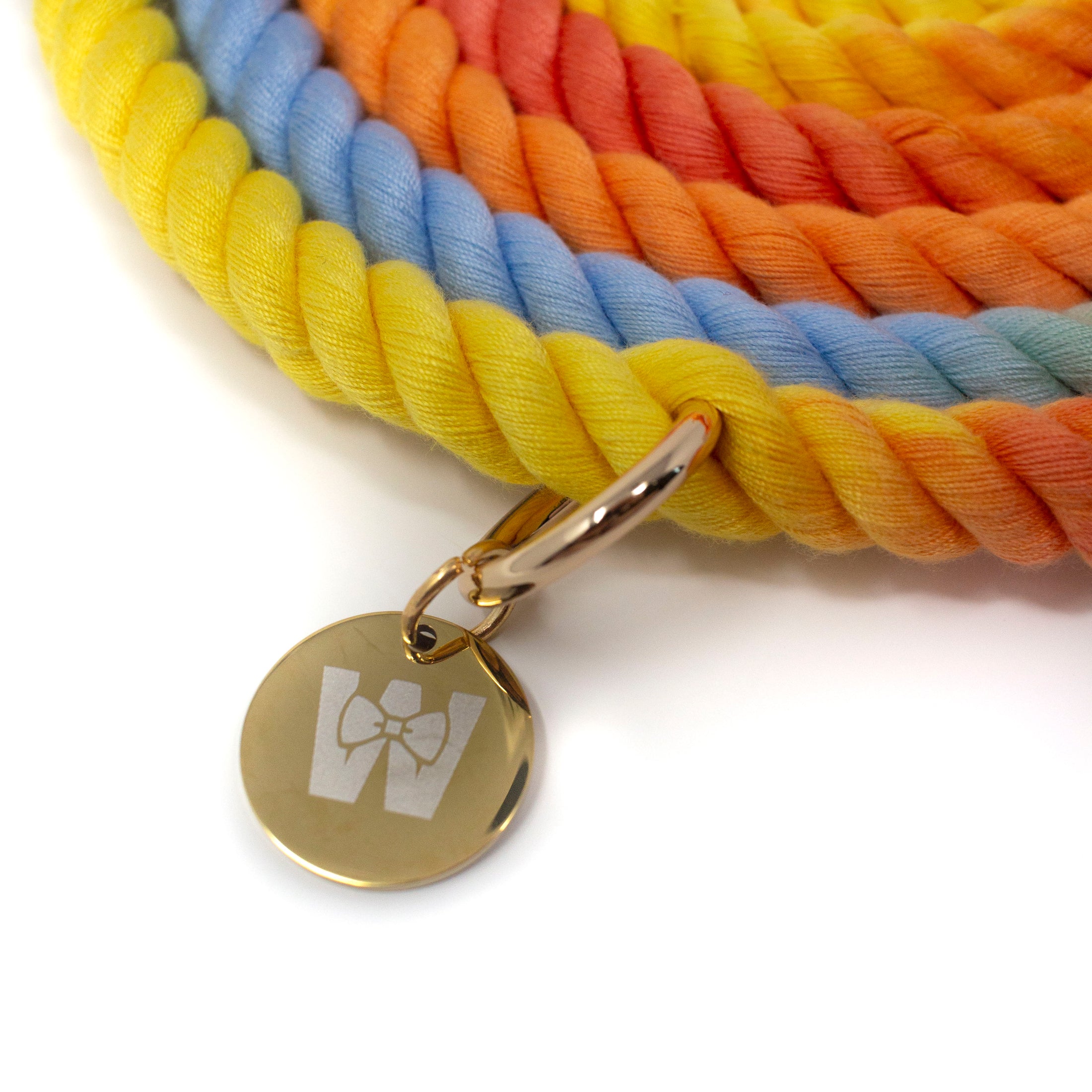 Colourful braided rope leash with a gold tag featuring The Woofdrobe logo on a white background